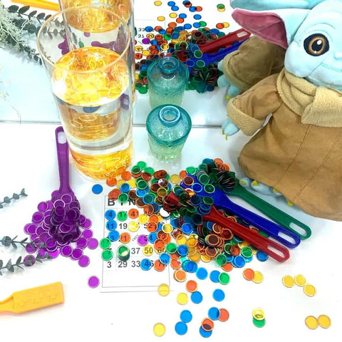 Magnetic Wand And Bingo Chips Set For Kids, colorful bingo chips around glasses, green wand, and bingo card on table.