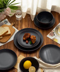Venus 12 Piece Stoneware Plates And Bowls Set With Trim Chip Resistant Dinnerware For Four Matte Black on a table.