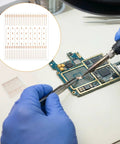 Hands using soldering iron with PCB Trace Repair Kit With 208 Red Copper Solder Pads For Mobile Phone Circuits on motherboard