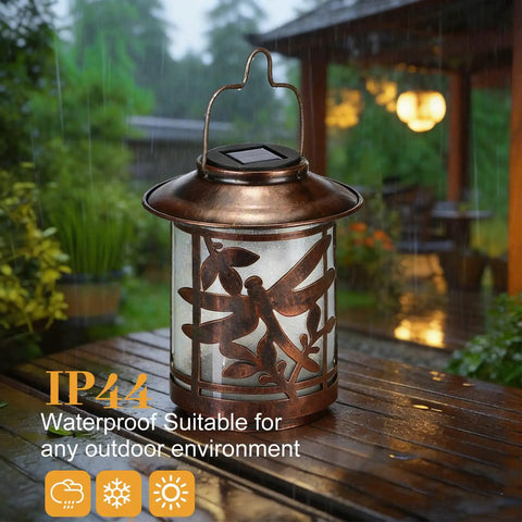 Outdoor Solar Lantern Dragonfly Metal Light Waterproof Garden Decor For Patio Courtyard Tabletop LED Night Ambiance Energy Saving Solar Powered Gifts For Mom Women 1 Pack showing dragonfly cutout design in rain, on wooden surface with garden in background.