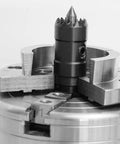 Close-up of a multi-tooth drive center in a four-jaw chuck for wood lathes, featuring a spring-loaded point for steady wood turning.