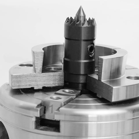 Close-up of a multi-tooth drive center in a four-jaw chuck for wood lathes, featuring a spring-loaded point for steady wood turning.