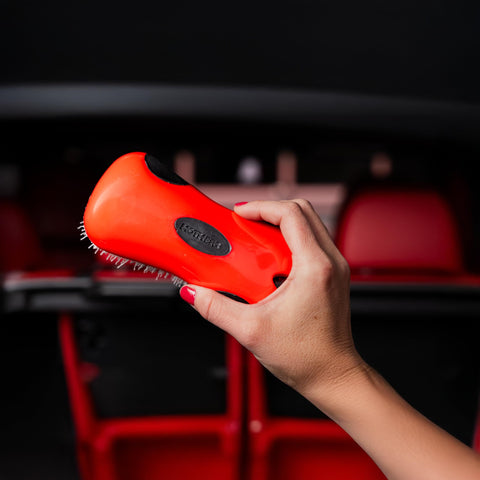 Hand holding a red Stiff Bristle Carpet And Upholstery Scrub Brush For Auto And Home Use, Heavy Duty Grime Buster, showing bristles