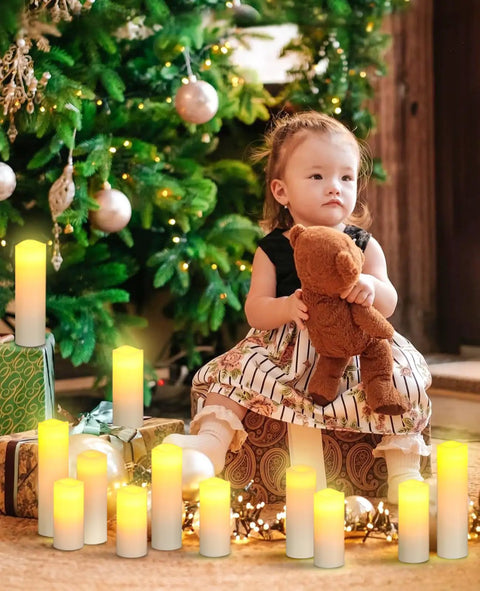 Child sitting near Christmas tree surrounded by Flameless LED Pillar Candles Set Of 12 Battery Operated With Remote And Timer Real Wax Look No Mess