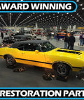Vintage yellow car on display at auto show with award-winning restoration parts signage.