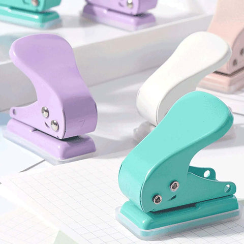 Compact colorful single hole punchers for card making, scrapbooking, and crafts shown in purple, white, and teal on a light surface.