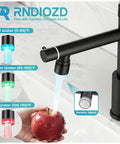 RNDIOZD LED Kitchen Faucet with Pull Down Sprayer, 2-Spout, Matte Black showing LED temperature indicator while rinsing an apple.