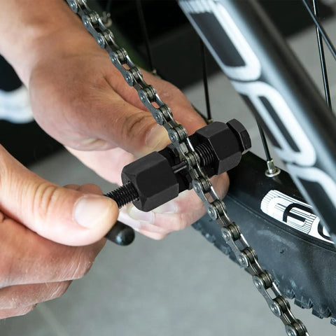 Person using Universal Bike Chain Breaker Tool And Cutter For 7 8 9 10 11 Speed Chains With Spare Replaceable Pin on bike chain.