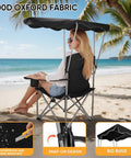 Woman relaxing on a black Folding Camping Chair With Canopy Shade And Cup Holders on a beach with palm trees.