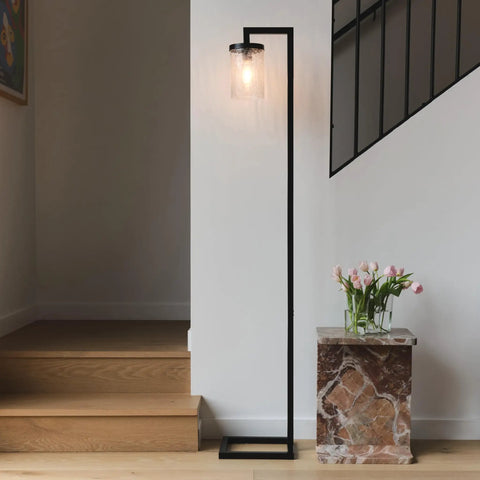 Modern black floor lamp with glass shade next to staircase and marble stand with tulips, minimalistic home decor