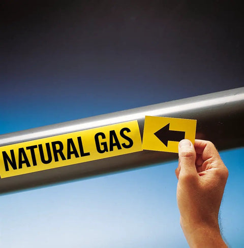 Self Adhesive Pipe Markers For Natural Gas 1X8 Inch Black And Yellow Labels on pipe, hand applying label with arrow.