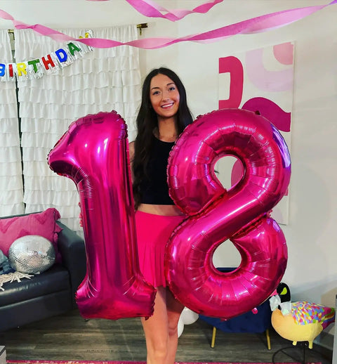 Hot Pink Number 8 Balloon 40 Inch Giant Foil Balloon For 8th Birthday Party Decor Epic Photo Backdrop Prop Large 8 Balloon For Party Supplies Bold Birthday Decor That Pops And Stays Put next to a number 1 balloon held by a woman indoors.
