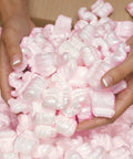 Hands holding pink packing peanuts for shipping and moving, 14 cubic feet antistatic void fill cushioning supplies.