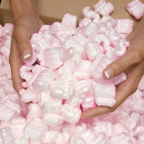 Hands holding pink packing peanuts for shipping and moving, 14 cubic feet antistatic void fill cushioning supplies.
