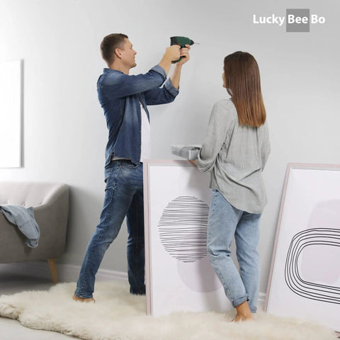 Couple using All In One Picture Hanging Kit With 100 Plus Pieces Including D Ring Screws Hooks Level And Stainless Steel Wire in living room