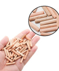 Hand holding 48 Pack 5Mm By 25Mm Wooden Dowel Pins With Fluted Beveled Ends For Shelves And Woodworking Hardwood Dowels For A Tight Friction Fit 0.2 Inch By 1 Inch Durable Wooden Pegs For Quick DIY Furniture Assembly, shown with a close-up inset of dowels on a surface.