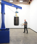 Built Tough Portable Jib Crane With Eight Foot Steel I Beam And 1000 Lb Capacity lifting a black barrel in a workshop.