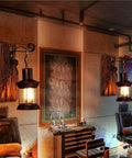 Top Shelf Rustic Wall Sconce Featuring Solid Wood Backplate And Vintage Industrial Metal Lantern Design, lit, in stylish interior.