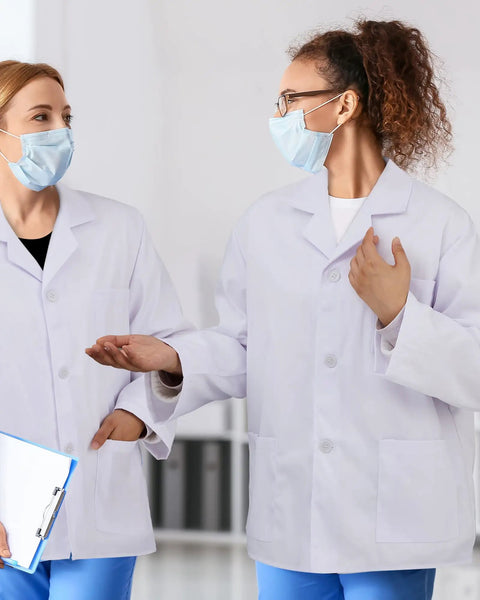 Two professionals wearing white unisex lab coat with 3 pockets for men and women, 3-piece set, clinic ready, discussing.