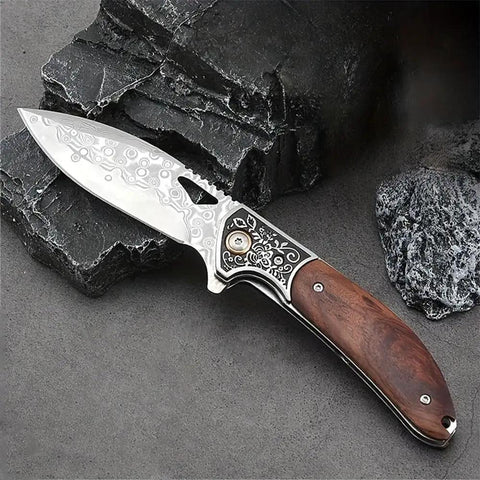 Dope Damascus Steel Folding Pocket Knife With 3.46 Inch Drop Point Blade, rosewood handle, on black rocks.