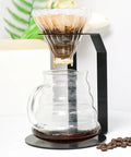 Premium Black Iron Coffee Dripper Holder With Heavy Duty Filter Stand brewing coffee into a glass server.