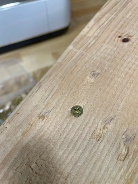 Close-up of a flat head Phillips drive screw in wood, representing The Real Deal 140 Piece Wood Screws Assortment Kit.
