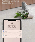 2K Indoor WiFi Baby And Pet Camera With 360 Degree Pan And Tilt AI Motion Tracking Crystal Clear Night Vision Two Way Audio Motion And Sound Alerts Alexa Compatible Easy Setup No Sweat Peace Of Mind monitoring notifications on smartphone while a cat tips over a potted plant on carpet.