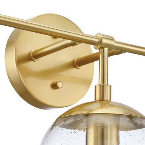 Close-up of Gracelyn Satin Gold 3-Light Bathroom Vanity Light fixture with round wall mount and clear seedy glass globe detail.