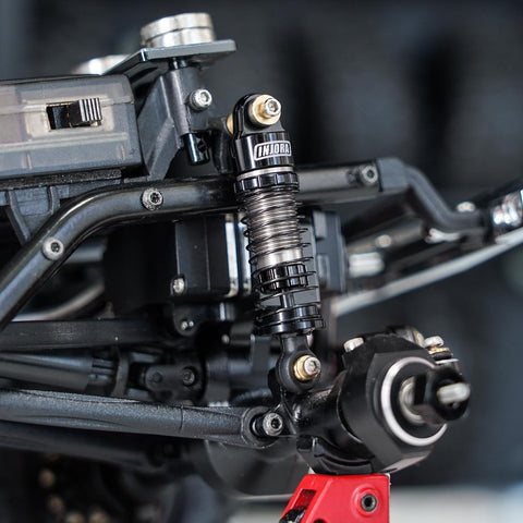 Close-up of 40mm Big Bore Oil Shock Absorber on 1/24 RC rig SCX24 FCX24M, black aluminum and nylon, threaded body visible.