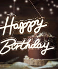 Lit Happy Birthday Neon Sign LED Light For Wall Backdrop Decoration With Split Design Reusable Approximately Forty Inch Total Length White Neon For Parties And Events glowing in front of a cake