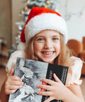 Child in Santa hat holding a 14 Piece White Charcoal Pencil Set For Drawing And Sketching, Pro Grade White Chalk Pencils box.