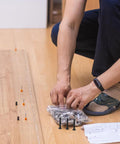 Person assembling with 141 Piece Furniture Bolts And Nuts Kit For Beds And Cribs, Aluminum Alloy Screws Set on wooden floor