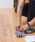 Person laying out heavy duty bed frame bolts and nuts kit with black coated steel screws for sturdy crib assembly.