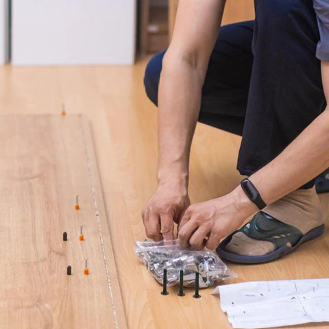 Person laying out heavy duty bed frame bolts and nuts kit with black coated steel screws for sturdy crib assembly.