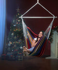 Indoor view of Oversized Hammock Chair With Rope Swing And Two Cushions, 500 Lb Capacity For Indoor Outdoor Relaxation, Rainbow design.