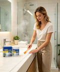 Woman applying Clear Waterproof Sealant For Tile Grout And Crack Repair Fast Dry Heavy Duty Leak Patch Tube in bathroom.