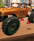 4-piece red metal RC car jack stands under an orange off-road RC truck with large knobby tires
