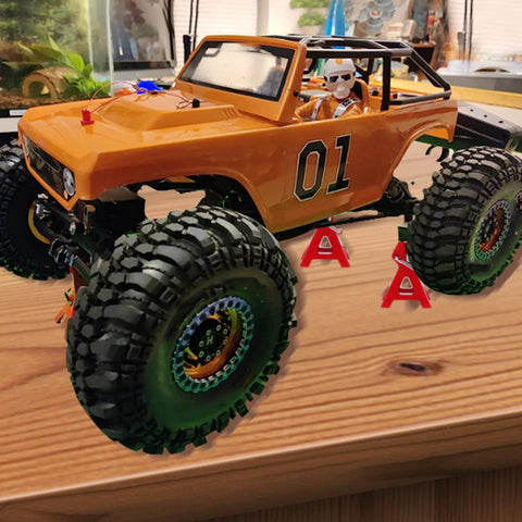 4-piece red metal RC car jack stands under an orange off-road RC truck with large knobby tires