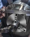 Close-up of a Three Jaw Self Centering Lathe Chuck 10 Inch With 0.24 To 9.84 In Clamping Range being measured with calipers.