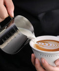 Pouring milk from Commercial Grade Stainless Steel Frothing Pitcher And Heavy Duty Die Cast Aluminum Tamper Set For Espresso Machines 12 Ounce Capacity 18 8 Construction Silver Finish Ideal For Lattes Cappuccinos And Macchiatos into cup with latte art