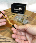 Hand holding a finished pen from Ten Pack Woodturning Pen Kits Titanium Silver Finish With Bonus Ten Covers And Dope Black Ink Ballpoint Slimline Rollerball Twist Set For Lathe Turning And Wood Blank Projects on table.