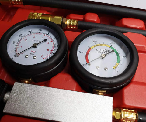 Front view of automotive cylinder leak-down tester with dual gauges and brass fittings in red case.