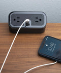 Compact Tabletop Power Strip Charging Station With 2 Tamper Resistant Outlets USB A And USB C Ports Rotated Plug Layout Ideal For Nightstands And Desks shown on a wooden desk.