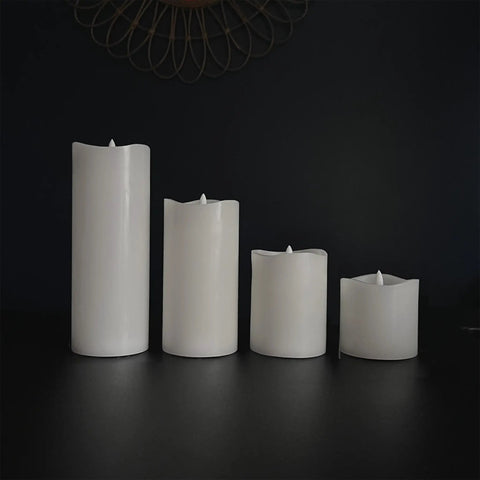 Four white wax flameless LED pillar candles in varying heights on dark background. Six Count Real White Wax Flameless LED Pillar Candles 3 By 4 Inches With Remote And Timer Dimmable Flicker Battery Powered Safe For Homes And Events For Cozy Home Decor And Vibe.
