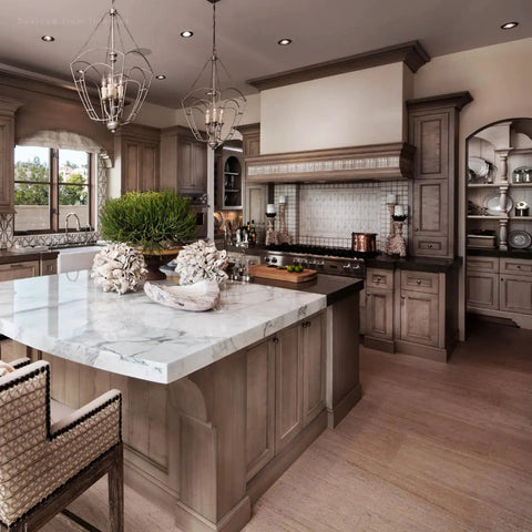 Modern kitchen with marble island, wood cabinetry, and elegant chandeliers.