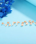 Rose Gold Unisex Stud Earrings Set For Women And Men 4 Pairs Of Dope Comfortable Studs In Circle Triangle Ball Shapes With 7.5mm Bars And 10mm Posts Easy Secure Butterfly Backs Hypoallergenic And Safe Everyday Wear. four rose gold stud earring pairs on blue background