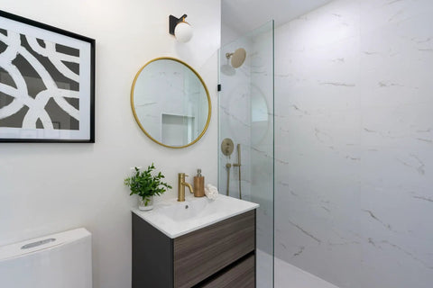 Bathroom interior with Alluria Wall Sconce Weathered Black With Autumn Gold Finish, round mirror, and glass shower