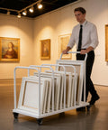Man pushing Heavy Duty Rolling Carton Stand With Adjustable Divider Slots And Smooth Lockable Wheels Solid Iron Flatbed Storage Cart built for moving art frames.