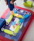 Hands using kid-friendly drill on Space Circuits Beginner Circuit Building Kit For Kids 52 Piece STEM Toy with lit circuit board