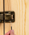 Inserting 50 Pack Black Aluminum Pop Rivets M4x25 Flange Blind Rivets into wooden surface, showing hand and latch detail